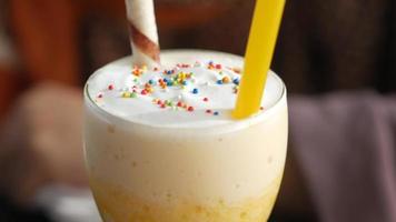 gros plan sur un milkshake à la vanille, avec un tube de wafer, de la paille jaune et des pépites video