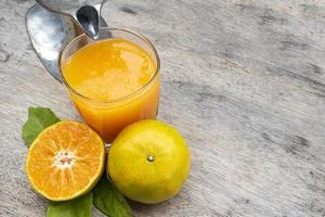 Orange juice in glass and fresh citrus around with Juicer hand press squeezer fruit on wood table. Copy space photo