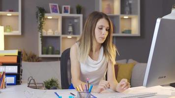 mulher cansada trabalhando no notebook na mesa no escritório em casa aconchegante. mulher que trabalha em home office está estressada e pensativa. video