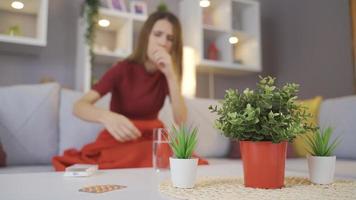 ziek vrouw is nemen geneesmiddel. de verstoord vrouw, verpakt in een deken, duurt haar geneesmiddel. video