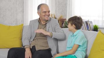 relación de abuelos. el abuelo está charlando con su nieto. dede está charlando con su nieto y lo abraza besándolo. video