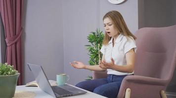 Das junge Mädchen ist zu Hause wütend. junges Mädchen, das mit Laptop arbeitet. Frau, die zu Hause mit Laptop im Wohnzimmer arbeitet, wird wütend. video