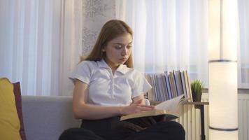 mulher lendo um livro à noite em casa. jovem lendo um livro em casa, focado no livro. video