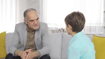 el abuelo da consejos a su nieto. el abuelo, que está en casa, está charlando con el nieto, y el abuelo está dando consejos a su nieto. video