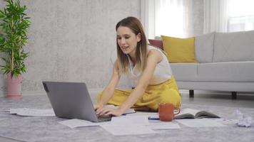 mujer joven con laptop y papeles trabajando en la oficina en casa. la mujer que trabaja en casa es pensativa y se muerde las gafas mientras mira la computadora portátil.