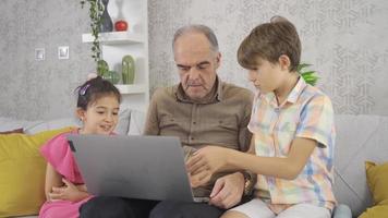 el anciano que no puede usar la computadora. nietos que ayudan a un abuelo que no entiende de tecnología. video