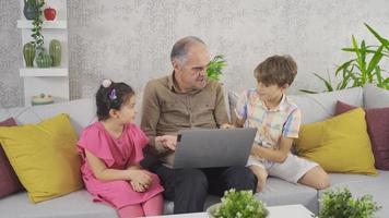 nietos que ayudan a un abuelo que no entiende de tecnología. nietos mirando la computadora portátil y ayudando a los abuelos. video