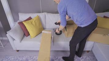 Backache. The man carrying heavy goods. The man carrying a parcel at home cannot lift the heavy parcel and sits on the couch, causing pain in his back. video