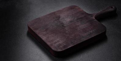 Wooden cutting board with kitchen appliances on a black concrete background