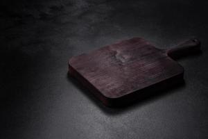 Wooden cutting board with kitchen appliances on a black concrete background photo