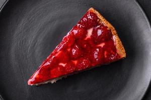 Homemade tasty cheesecake with jelly and raspberry berries on a black plate photo