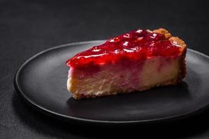 Homemade tasty cheesecake with jelly and raspberry berries on a black plate photo