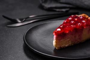 Homemade tasty cheesecake with jelly and raspberry berries on a black plate photo