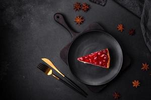 Homemade tasty cheesecake with jelly and raspberry berries on a black plate photo