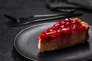 sabroso pastel de queso casero con gelatina y frambuesas en un plato negro foto