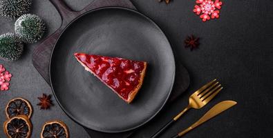 Homemade tasty cheesecake with jelly and raspberry berries on a black plate photo