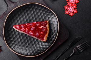 Homemade tasty cheesecake with jelly and raspberry berries on a black plate photo