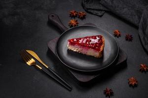 Homemade tasty cheesecake with jelly and raspberry berries on a black plate photo