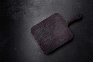 Wooden cutting board with kitchen appliances on a black concrete background