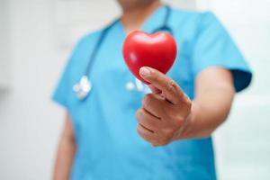 Asian woman doctor holding red heart for health in hospital. photo