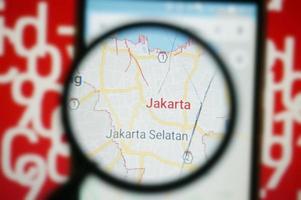Jakarta, Indonesia maps under magnifying glass with Red Covid-19 text Background. photo