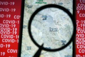 Iran country on google maps under magnifying glass with Red Covid-19 text Background. photo