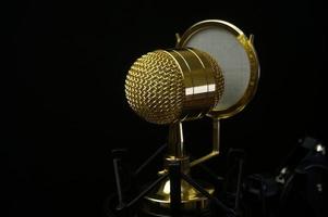 condensador de micrófono dorado. aislado sobre fondo negro. enfoque selectivo foto