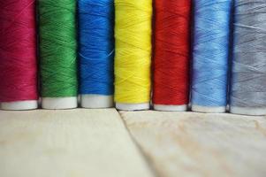 Colorful spools of thread on wooden table photo