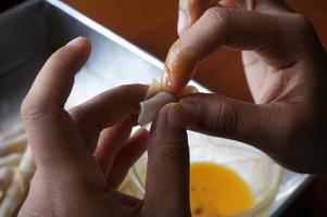 el proceso de hacer o cocinar un kacang sembunyi, un bocadillo popular de indonesia. frijoles envueltos en una piel de masa de harina. frito con aceite y azúcar líquido. foto