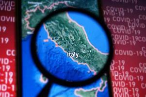 Italy country on google maps under magnifying glass with Red Covid-19 text Background. Selective Focus. photo