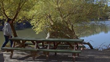 vieil homme assis sur un banc au bord du lac et regardant le lac video