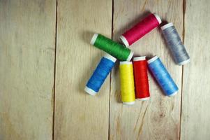 Top view colorful spools of thread on wooden table photo