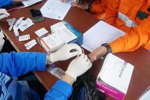 a health worker performs a finger prick test for HIV, Selective Focus photo