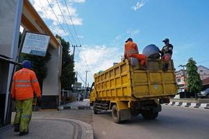 sangatta, kalimantan oriental, indonesia, 2020 - los trabajadores tiran un bote de basura en un camión de basura al lado de la carretera. foto