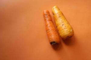 dos zanahorias diferentes aisladas sobre fondo naranja. foto