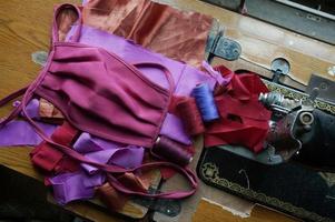 Homemade protective mask and pieces of cloth on wooden of manual sewing machine. Selective Focus. photo