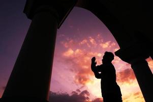 sangatta, este de borneo, indonesia, 2020 - un hombre reza fuera de la mezquita al fondo de la puesta de sol foto