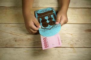 Hand of young kid holding indonesian money. Rupiah, IDR money. photo