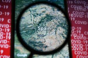 Spain country on google maps under magnifying glass with Red Covid-19 text Background. Selective Focus. photo