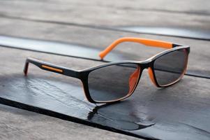 Orange spectacles on wooden table. photo