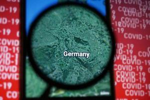 país de alemania en google maps bajo lupa con fondo de texto rojo covid-19. enfoque selectivo. foto
