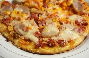 Delicious homemade pizza with sweet corn, beef sausage, Shredded beef, cheese and sausages on yellow background, close up with selective focus. photo