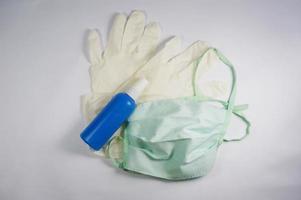 Surgical mask, medical gloves and sanitizer in bottle. White background. photo