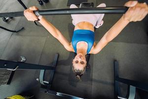 Woman doing exercises with barbell on a bench press training photo