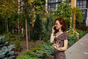 Cute girl talking on mobile phone on modern city background photo