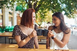 Two friends drinking coffee - women clinking with cups of coffee photo