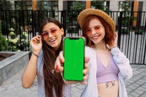 Girlfriends shows their phone to the camera photo