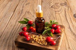 serum for skin care of the face in a glass bottle with a dropper stands on a wooden podium among the seeds and fruits. care for tired skin. photo