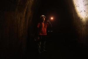 Female digger with flashlight explores the tunnel photo