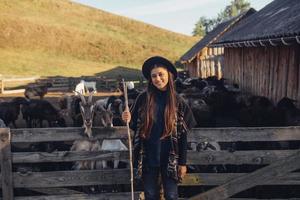 A young beautiful woman near a pen with goats photo